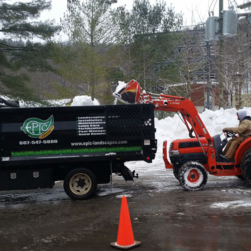 Using a tractor and dump truck to remove large piles of snow.
